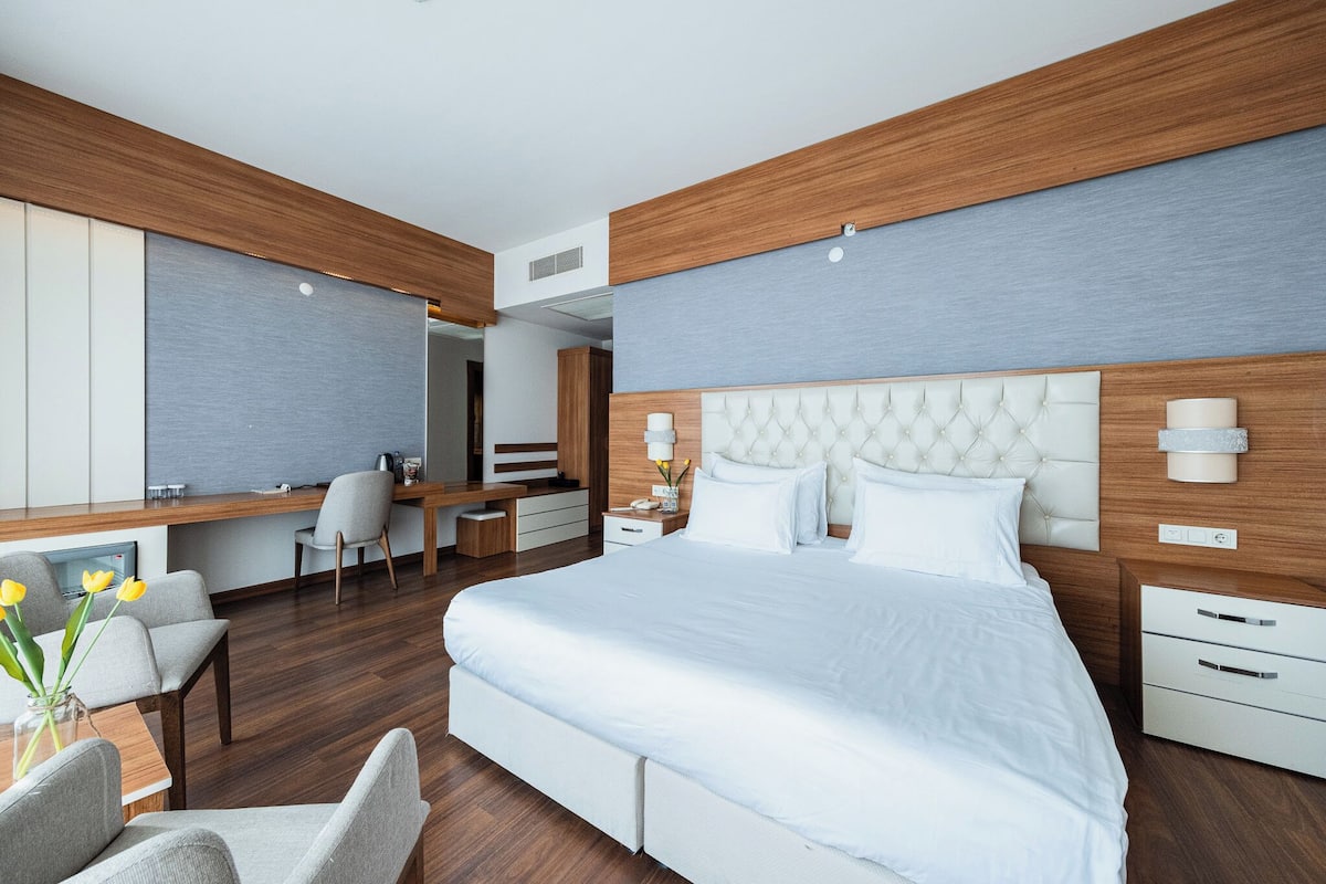 A modern hotel room with a large bed, a desk, and a seating area.