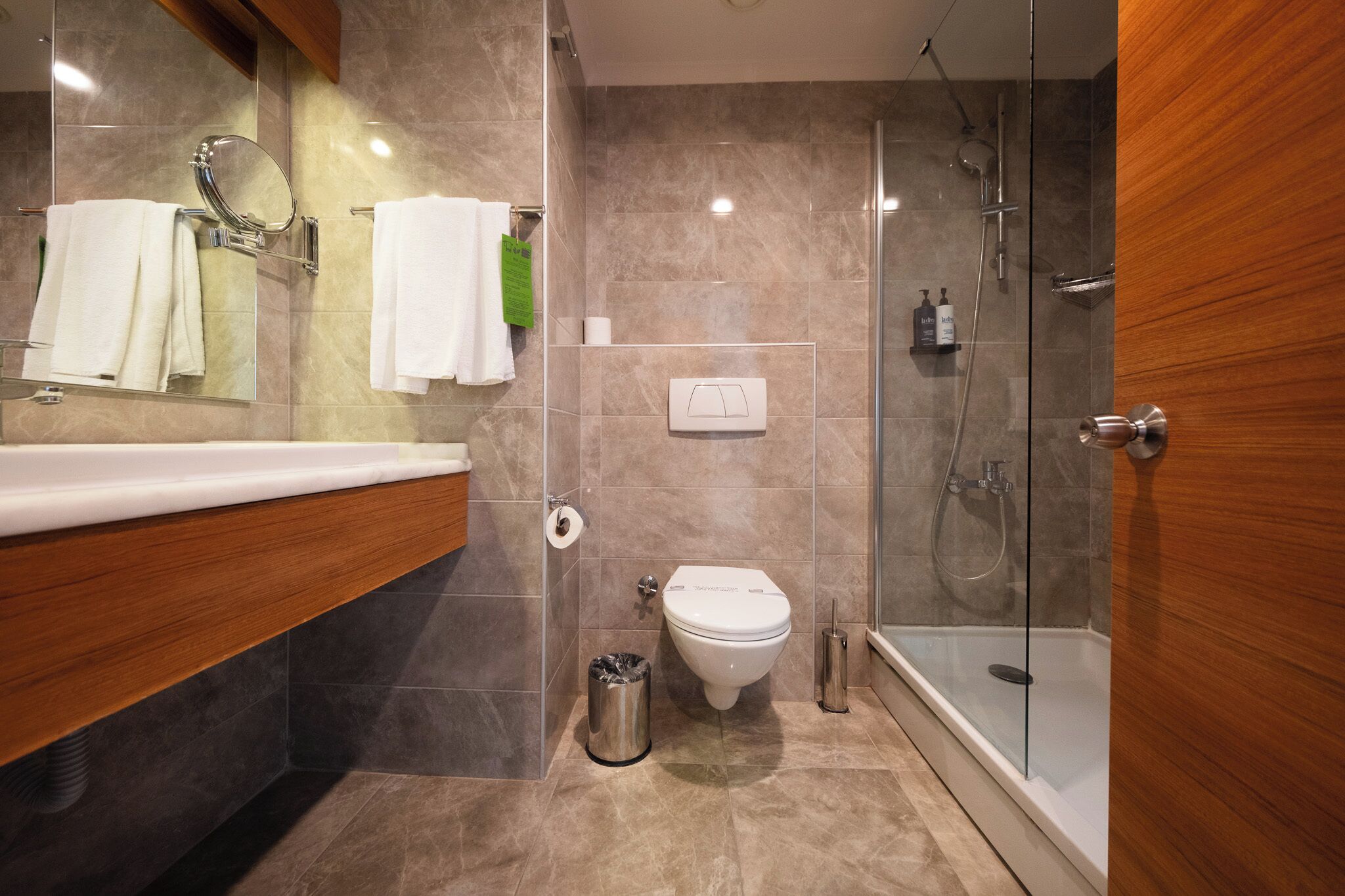 Un baño moderno con ducha de vidrio, inodoro y lavabo con espejo.
