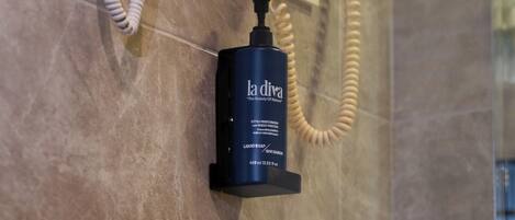 A bathroom with a marble floor, a white telephone, a hairdryer, and a bottle of LaDiva liquid soap.