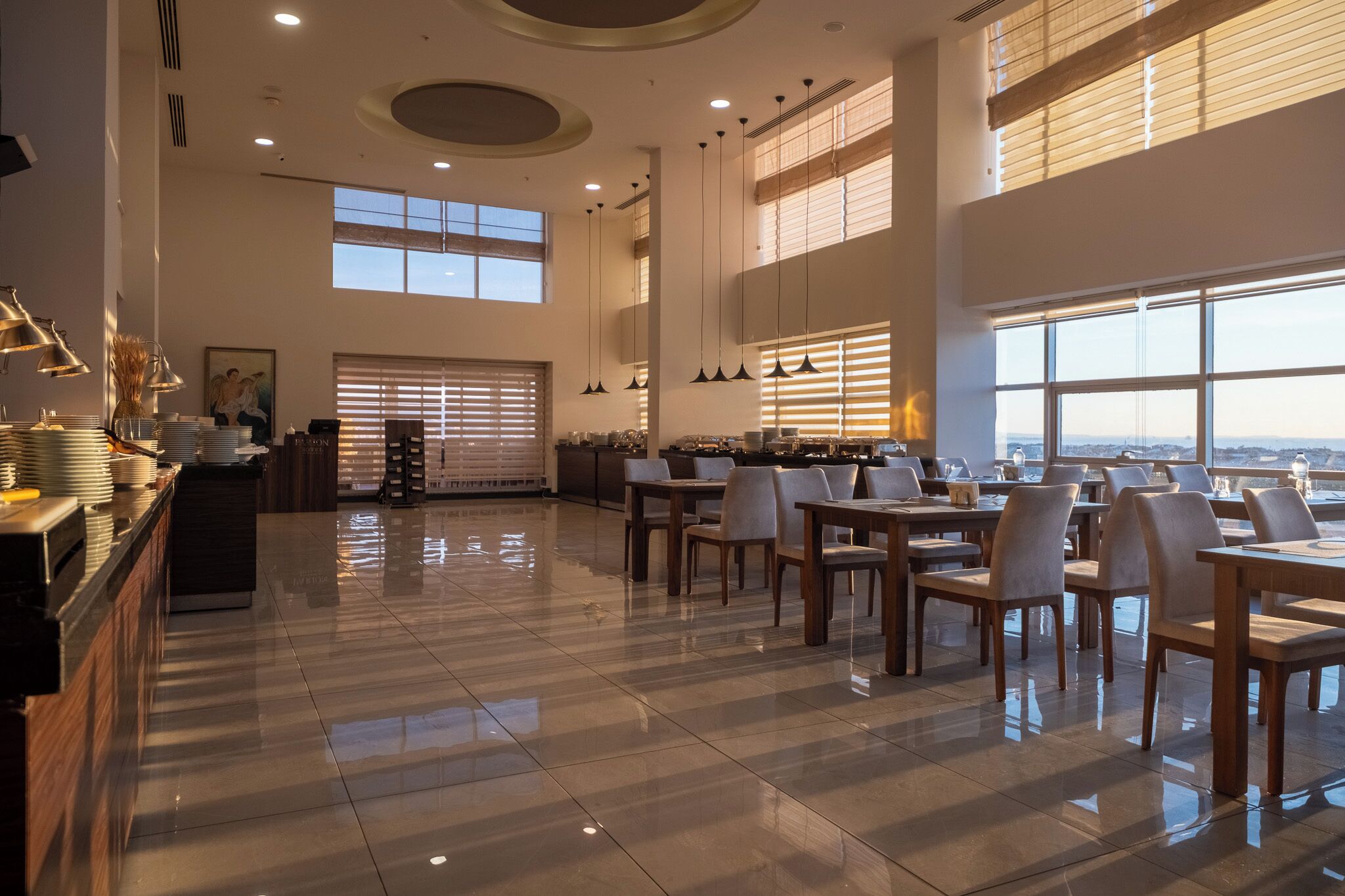 A spacious dining area with high ceilings, large windows, and modern lighting fixtures.