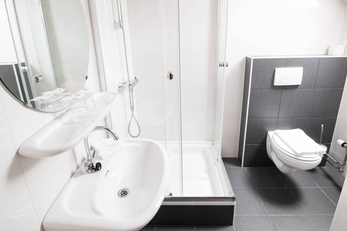Een moderne badkamer met een witte wastafel, spiegel en douche.