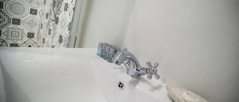 A white bathtub with a modern faucet and a soap dish.