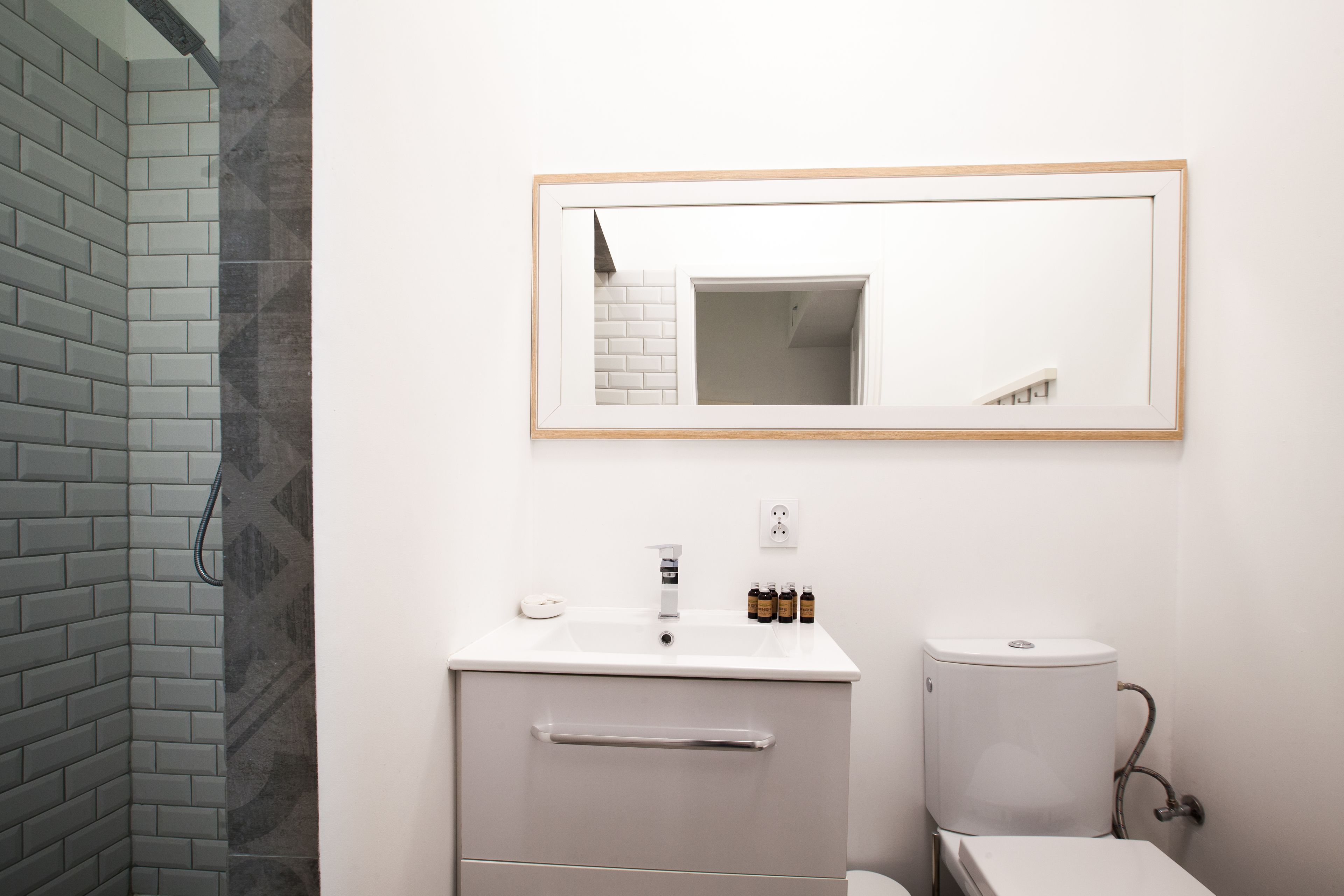 Une salle de bain avec un lavabo blanc, un miroir et des toilettes.