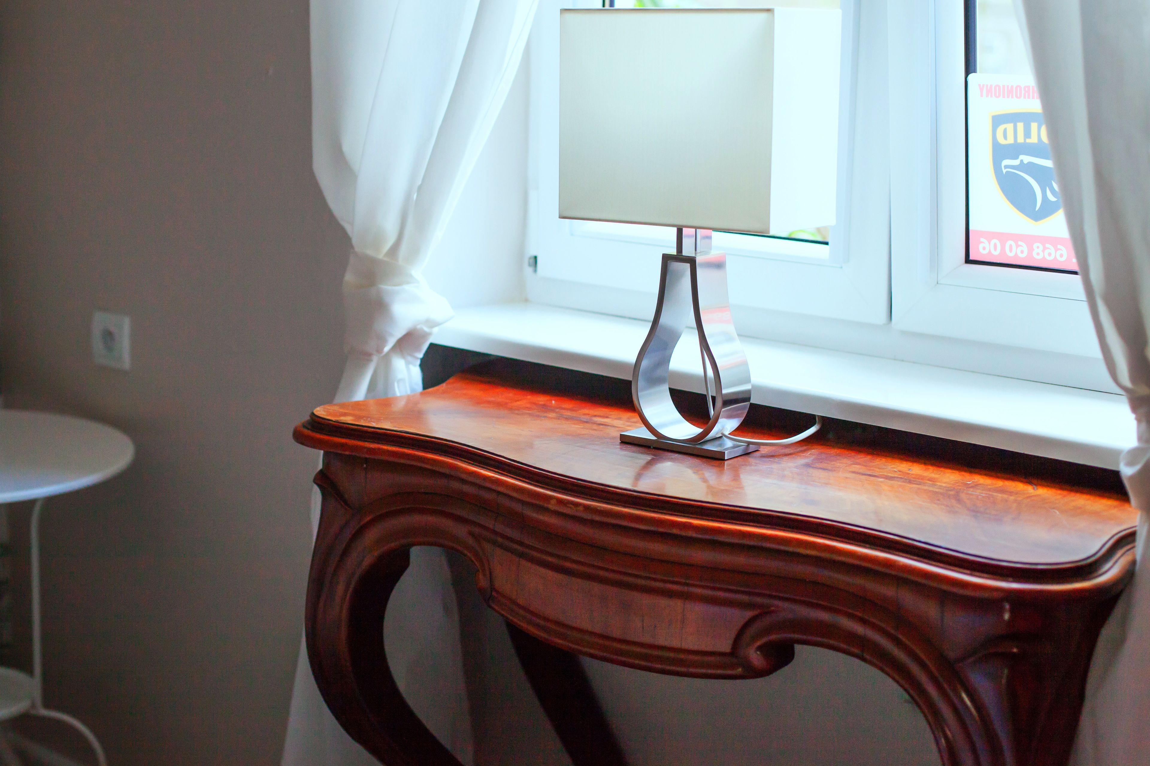 A wooden table with a lamp in a room with a window.
