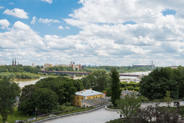 Vista al río con un edificio amarillo, un puente y un estadio al fondo.