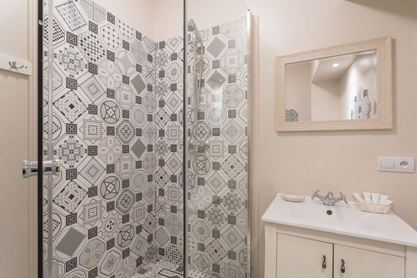 A bathroom with a patterned shower door, a sink with a mirror, and a cabinet with drawers. - Ego Apartments Old Town (Warsaw)