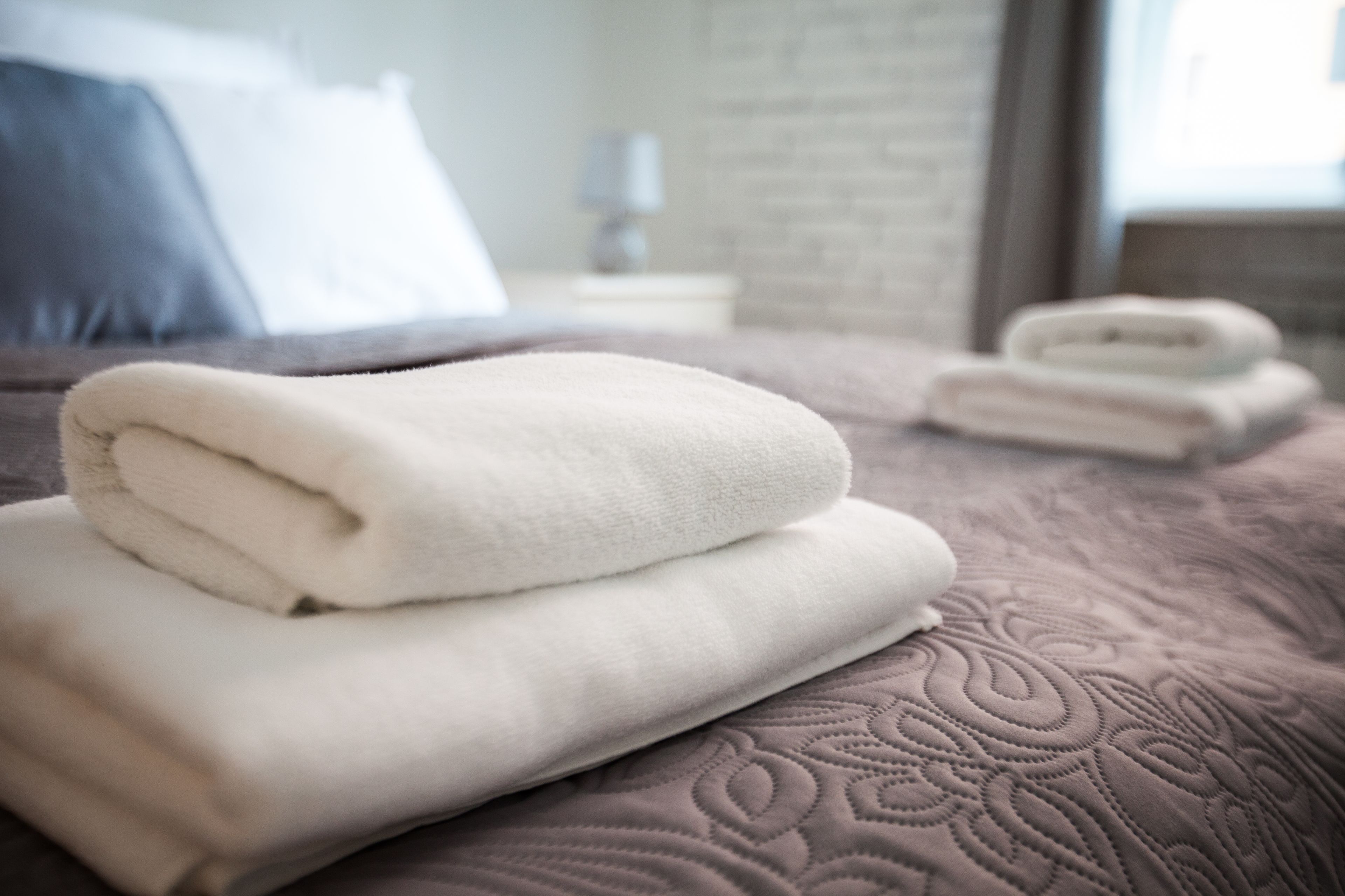 A neatly made bed with folded white towels and a patterned bedspread.