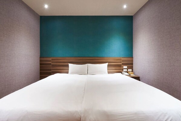 Une chambre d’hôtel avec un grand lit, une tête de lit en bois et un mur d’accent de couleur turquoise.