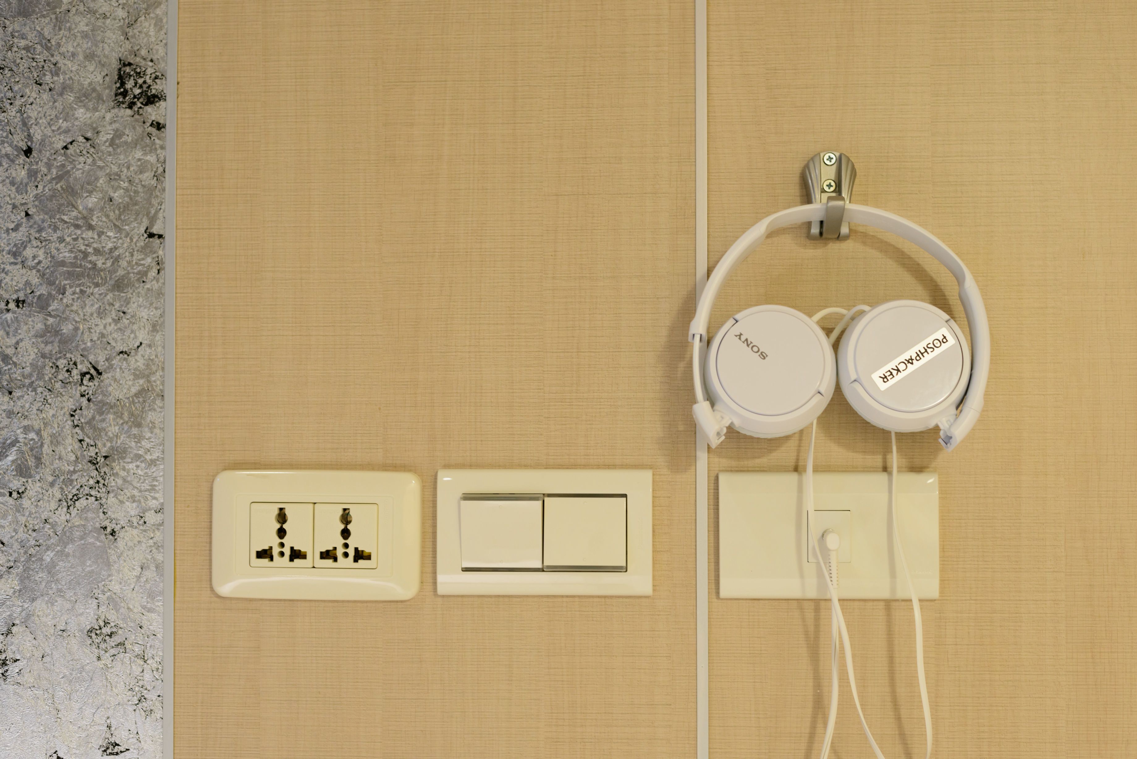 Presta d'electricitat amb interruptor, una presa amb un endoll i uns auriculars penjats d'un ganxo.