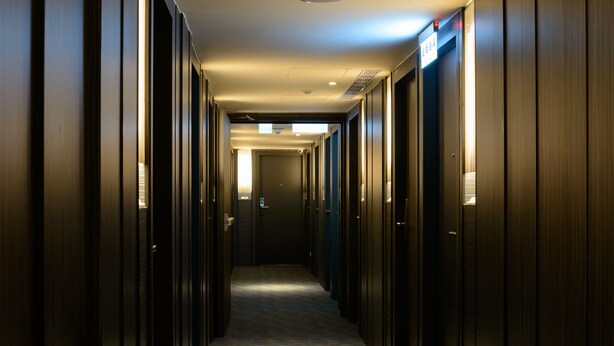A hotel hallway with a carpeted floor and wooden walls. - Poshpacker Hotel (Taipei)