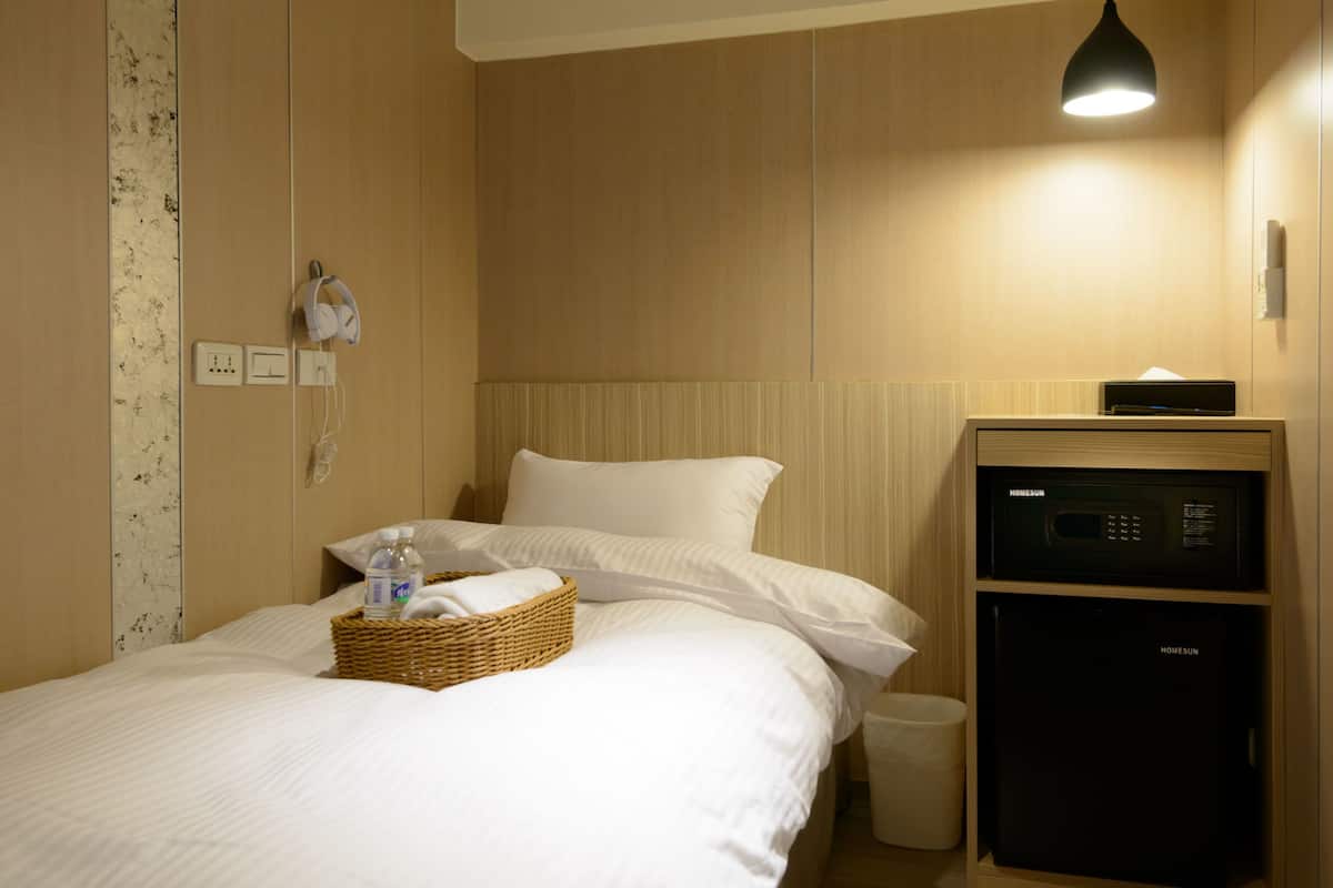A hotel room with a bed, bedside table, and a small cabinet.