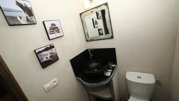 Een badkamer met een toilet, een wastafel met een zwarte kom en drie ingelijste foto's aan de muur.
