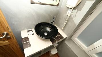 Een badkamer met een wastafel, spiegel en telefoon.