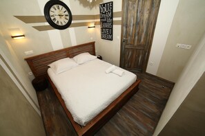 A bedroom with a wooden bed, a wall clock, and a motivational quote sign. - Hôtel de France (Lens)