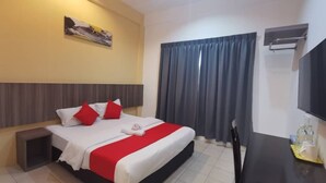 Una habitación de hotel con cama, escritorio, televisión y ventana con cortinas.
