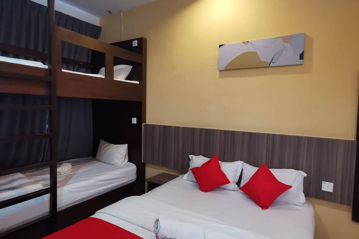 Une chambre d’hôtel avec un lit superposé, un lit simple et une touche de couleur rouge sur la couvre-lit.