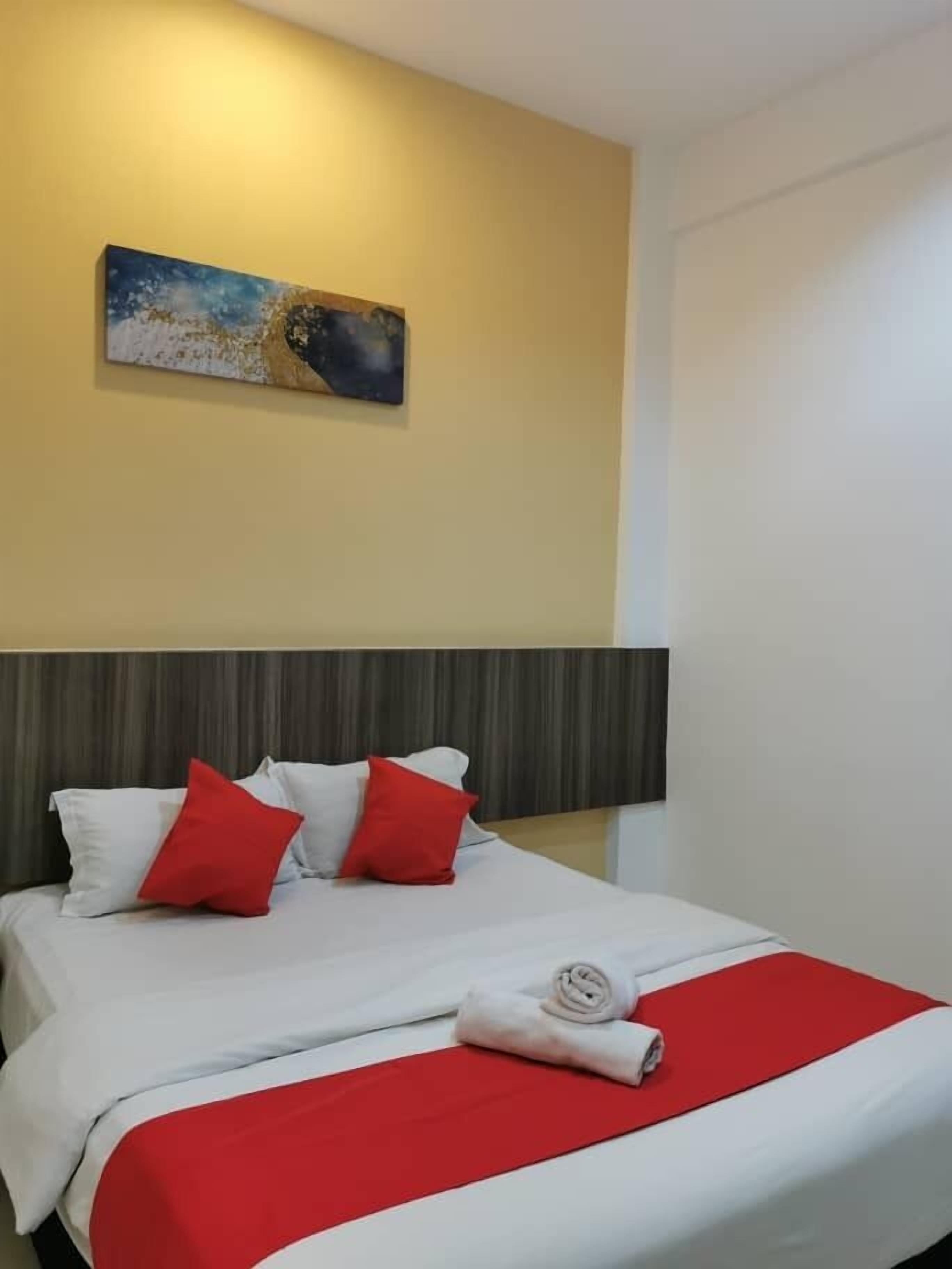 Ein Hotelzimmer mit Bett, Kopfteil, einem Bild an der Wand und einer roten und weißen Bettdecke.