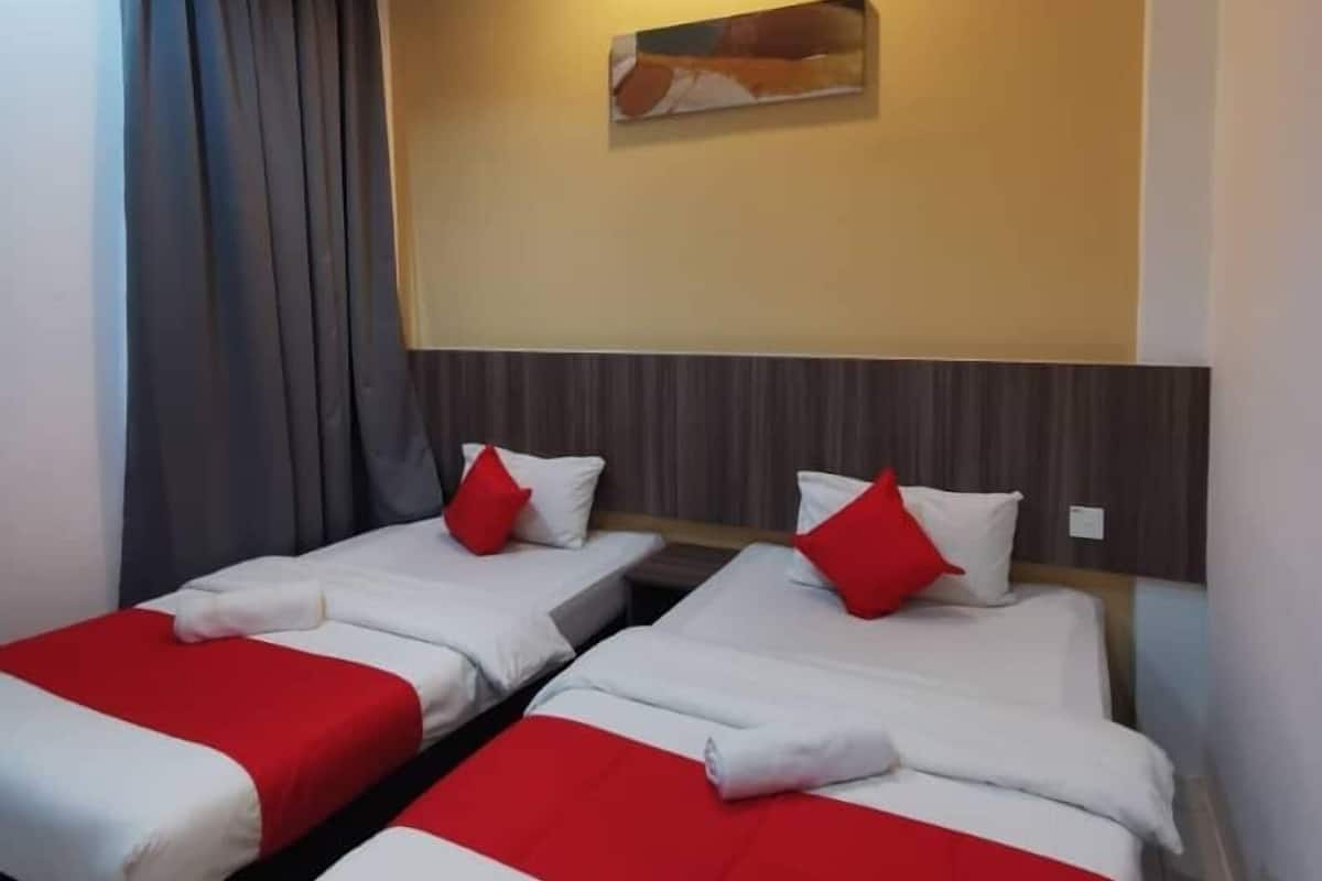 Une chambre d’hôtel avec deux lits, chacun doté d’une literie rouge et blanche, d’une tête de lit, d’un tableau accroché au mur et d’un luminaire au plafond.