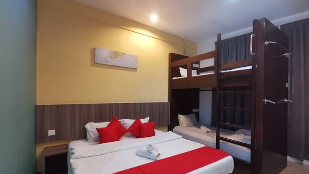 Una habitación de hotel con una cama grande, dos camas más pequeñas, una cama nido de madera, una mesita de noche y una obra de arte colgada en la pared.