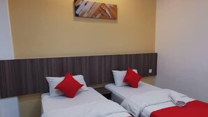Una habitación de hotel con dos camas, cada una con ropa de cama blanca y almohadas rojas, un cabecero de madera y una obra de arte colgada en la pared.