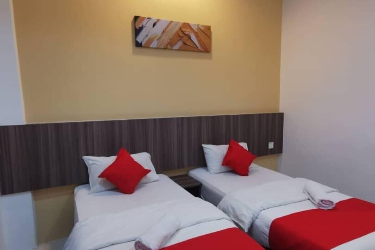 Une chambre d’hôtel avec deux lits, chacun doté de draps blancs et d’oreillers rouges, d’une tête de lit en bois et d’une œuvre d’art accrochée au mur.