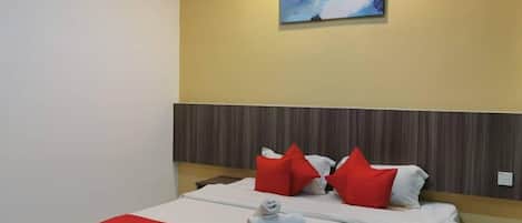 Una habitación de hotel con una cama, ropa de cama roja y blanca, un cabecero de madera y un cuadro en la pared.