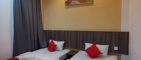 A hotel room with two beds, each with red and white bedding, a headboard, a wall-mounted artwork, and a curtain.