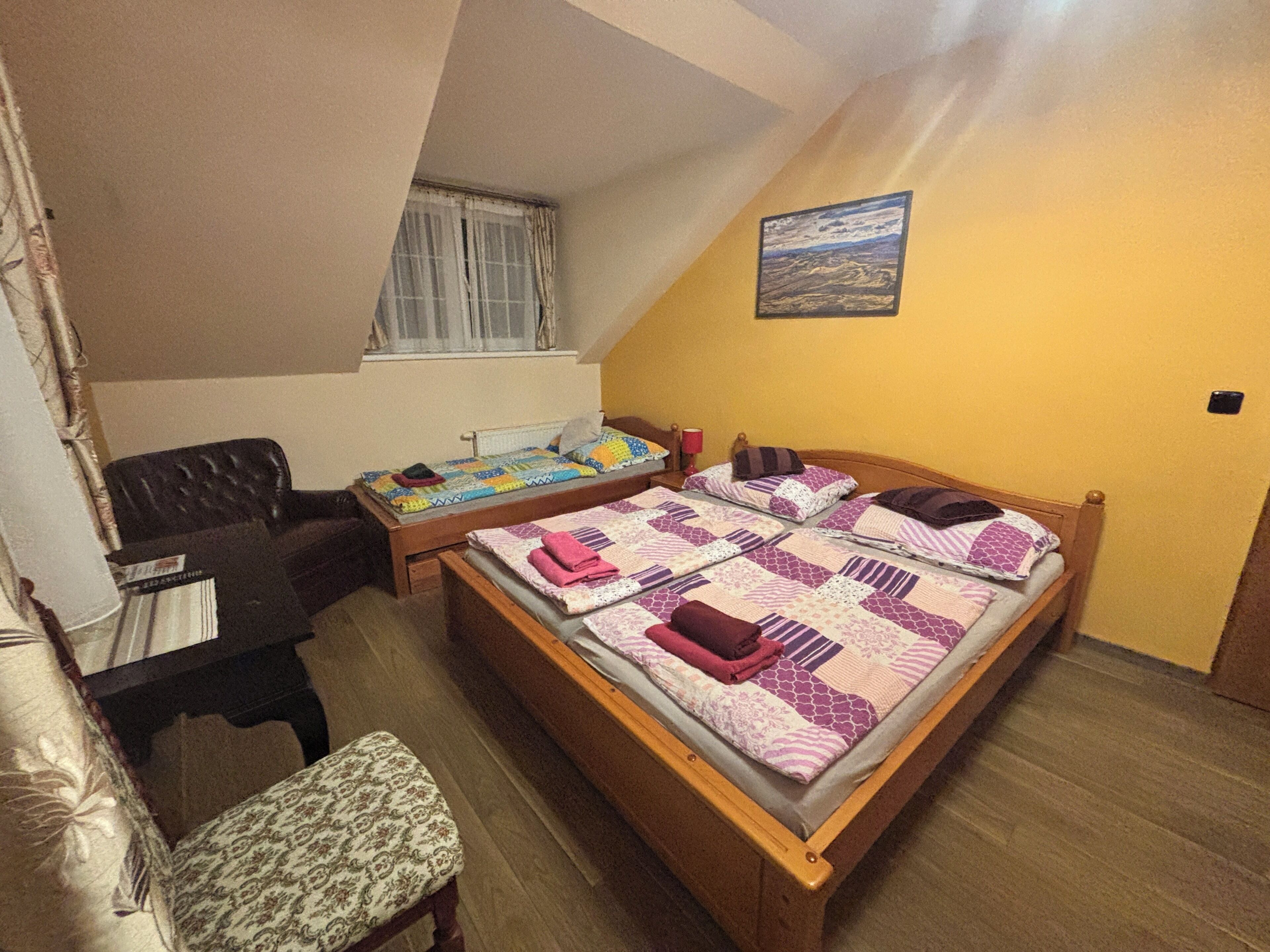 A bedroom with two beds, a desk, a chair, and a window.