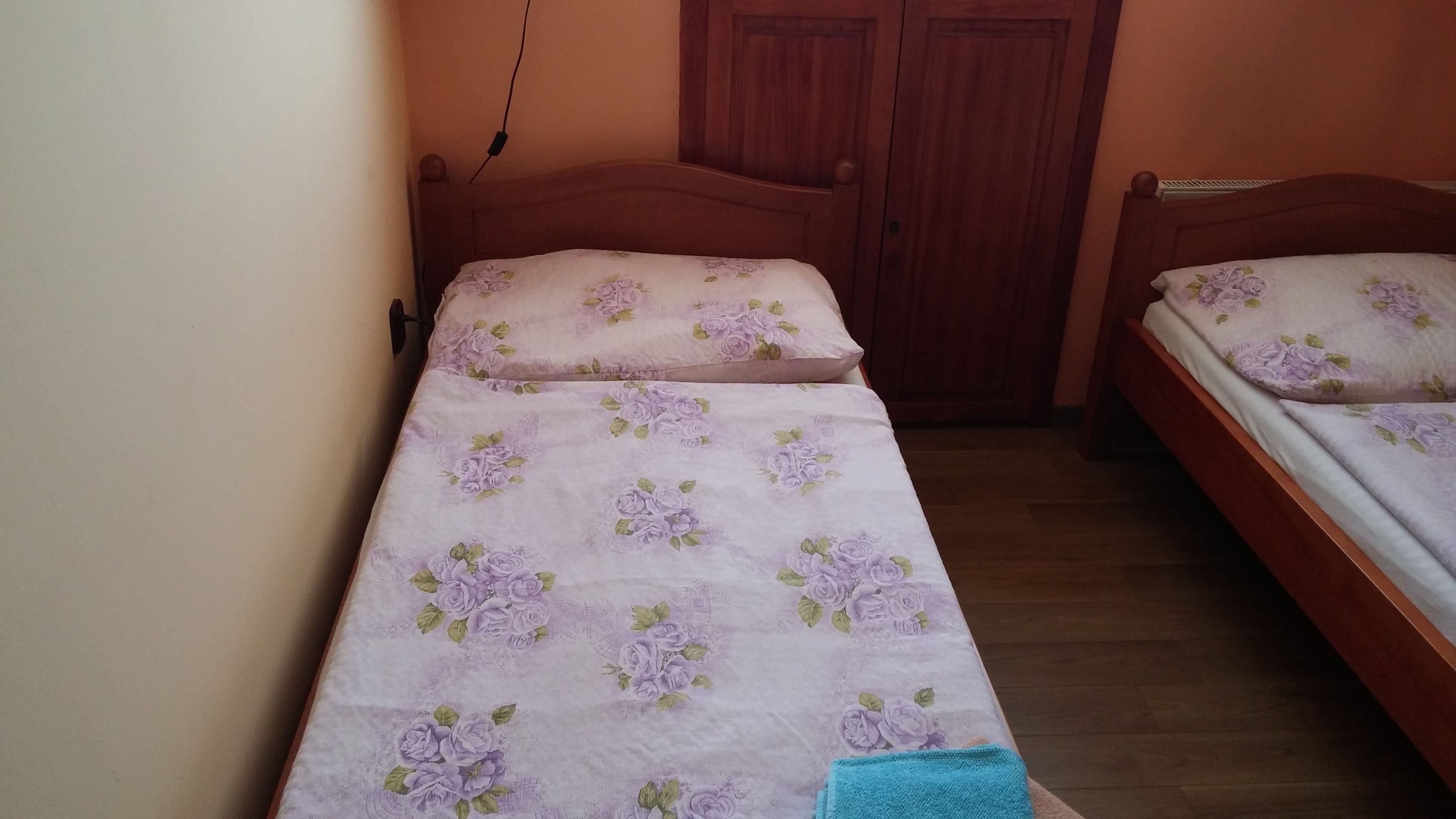 A small, single-bed room with a wooden headboard and a floral bedspread.
