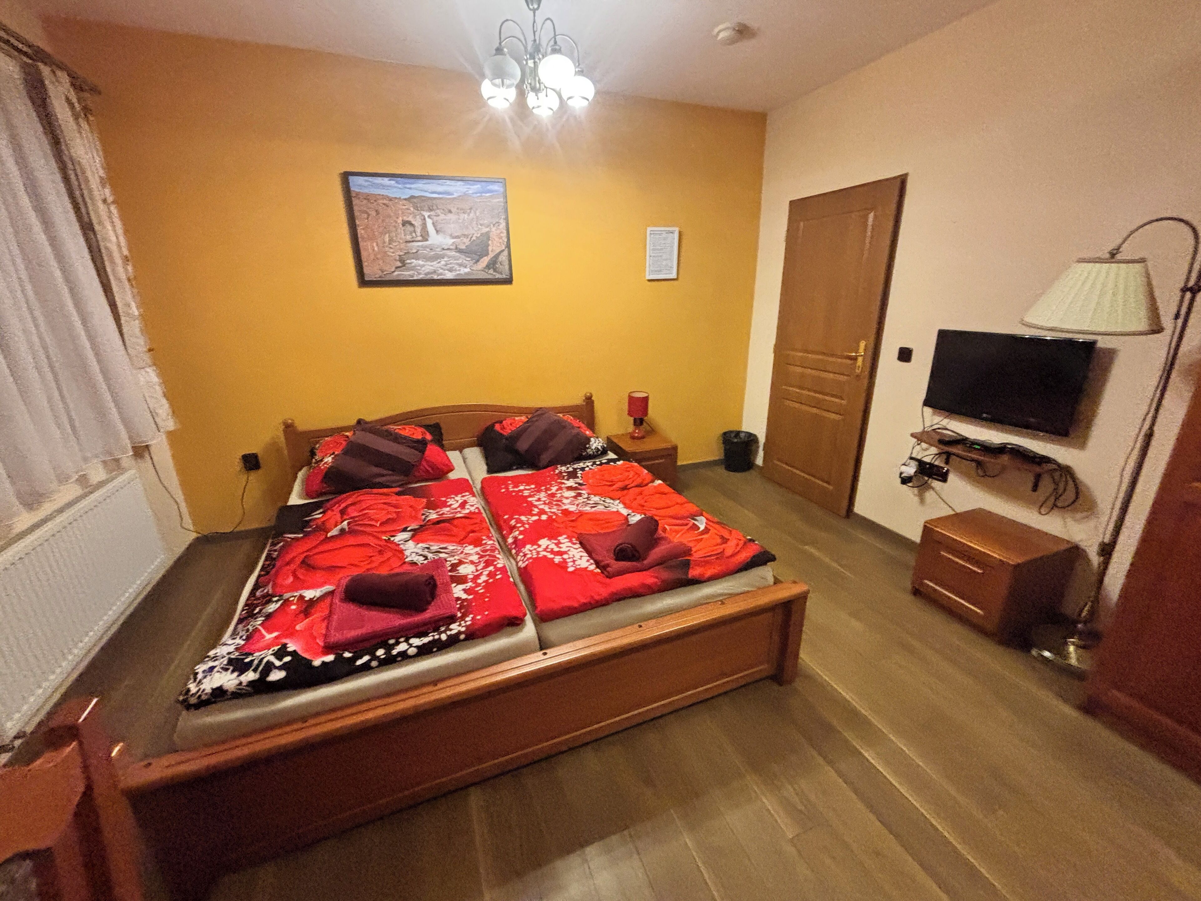A bedroom with a bed, a television, a lamp, and a door.