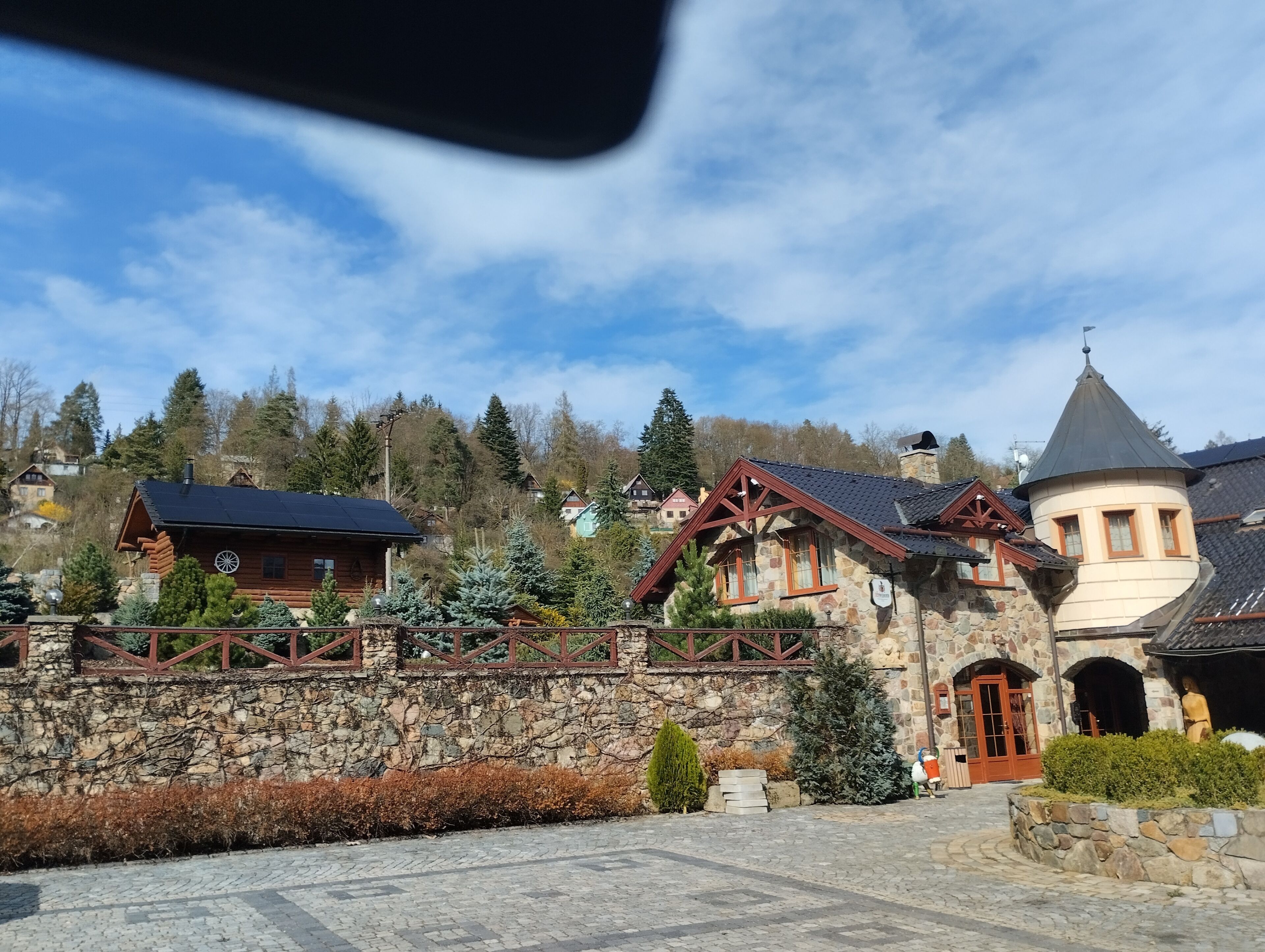 Un edificio de piedra con fachada de madera, una pared de piedra y un pequeño jardín.