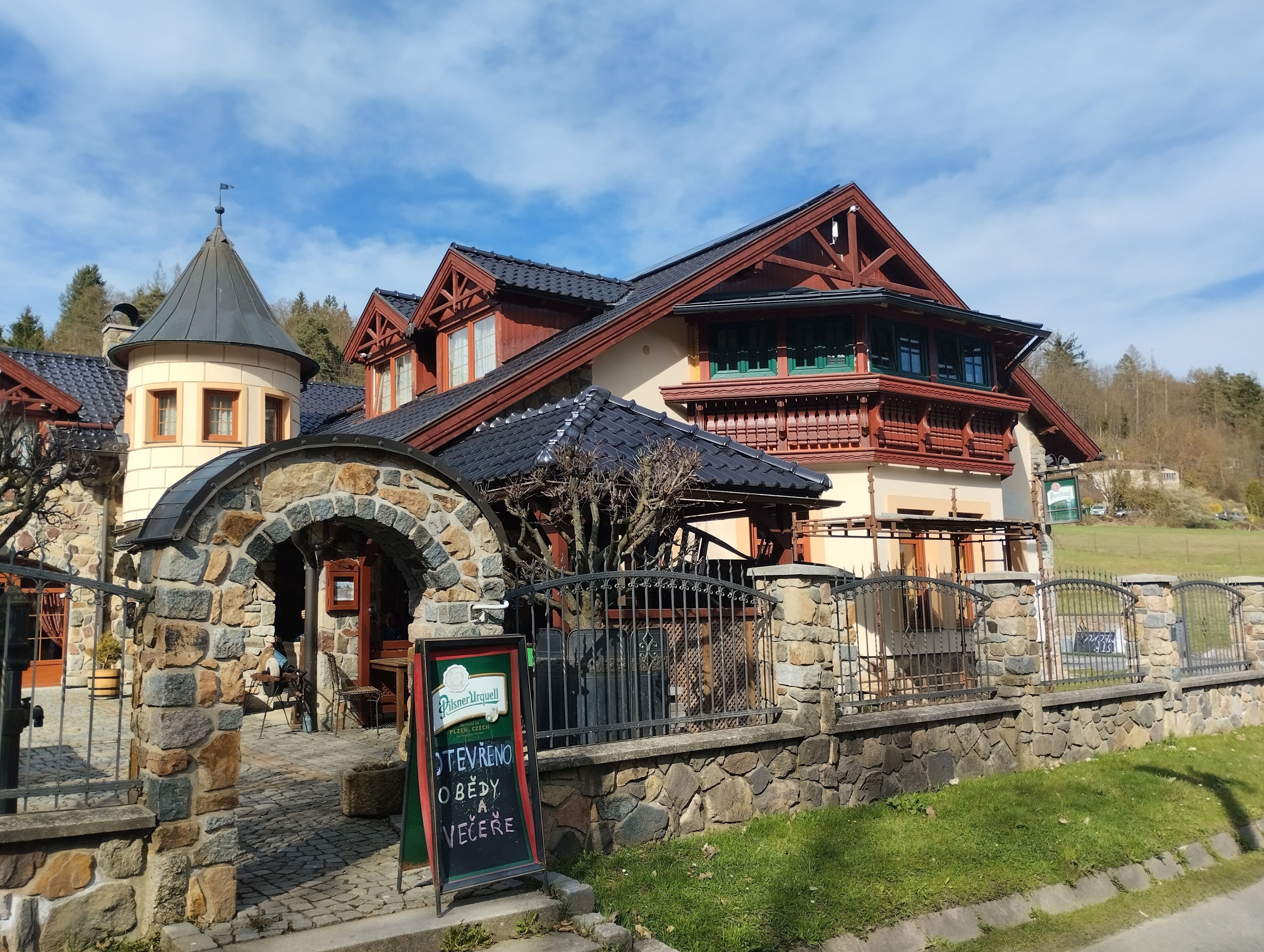 A traditional building with a stone archway entrance, a signboard, and a fenced area.