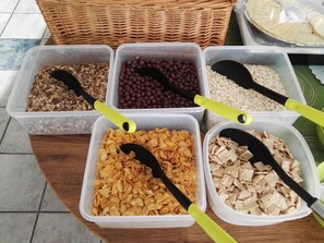 Four plastic containers with different types of cereal and a wicker basket in the background.