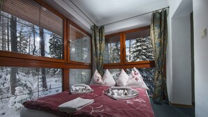 A bedroom with a large window, wooden blinds, and a bed with pillows and towels. - Penzion Pleso (Štrba)