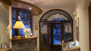 A reception area with a stone wall, a wooden counter, a lamp, and a chair. - Penzion Pleso (Štrba)