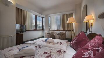 A hotel room with a large bed, two bedside lamps, a TV, and a view of the outdoors.