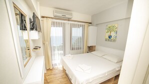 A bedroom with a bed, a bedside table, a mirror, an air conditioner, and a window with curtains.