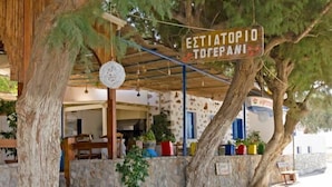 A rustic outdoor seating area with a wooden pergola, potted plants, and a sign reading "ΕΣΤΙΑΤΟΡΙ ΤΟΡΕΠΑΝΙ". - Gerani Studios (Astypalaia)
