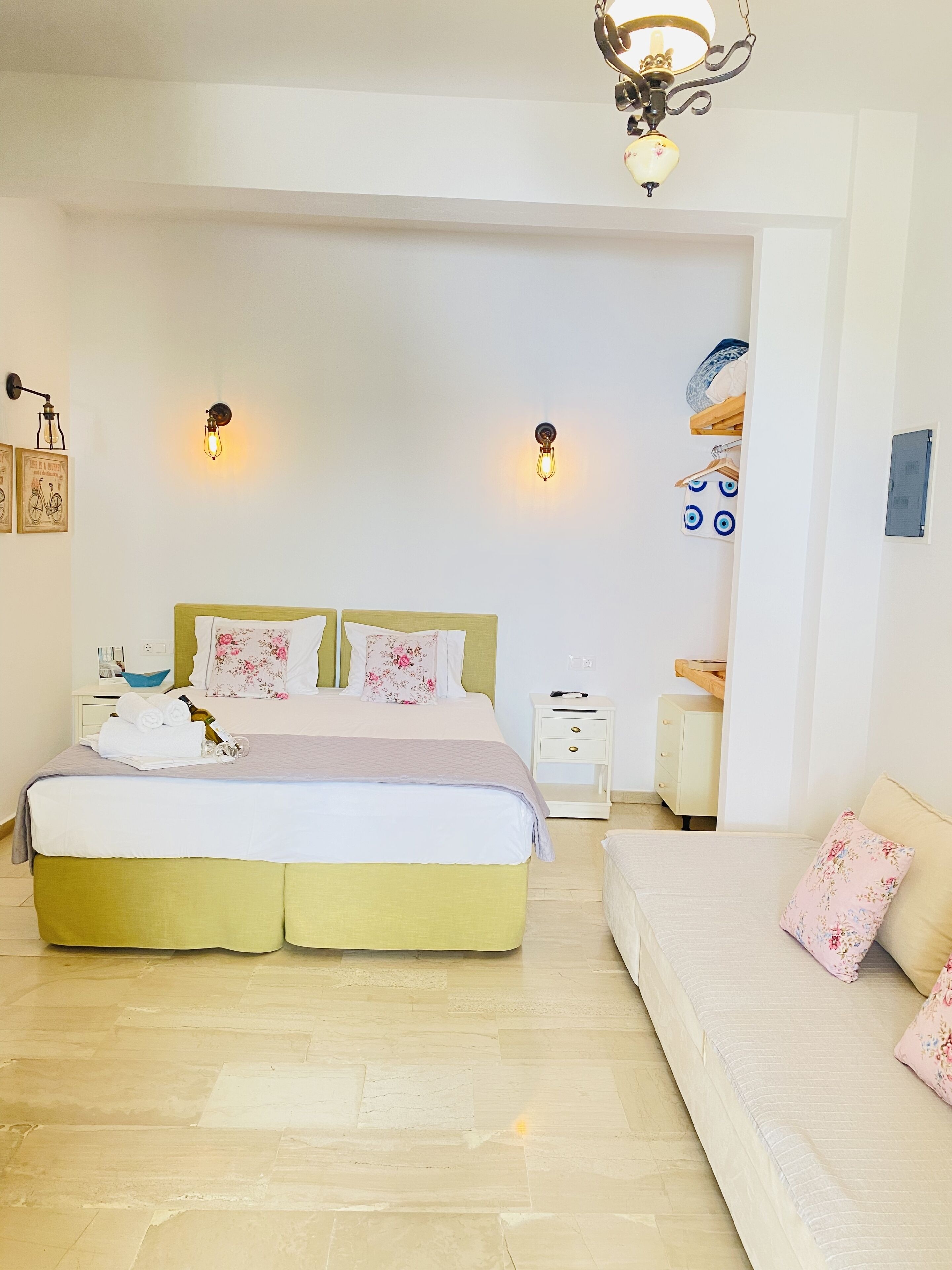 A bedroom with a large bed, bedside tables, a sofa, and decorative wall sconces.