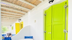 A room with a white ceiling, a green door, and a table with chairs. - Gerani Studios (Astypalaia)