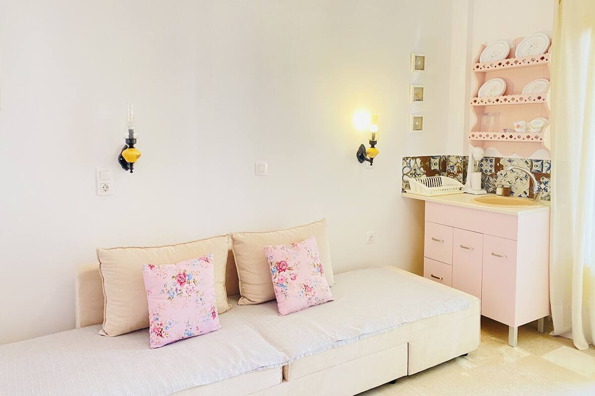 A bedroom with a bed, a bedside table, a wall-mounted shelf with decorative items, and a wall sconce.