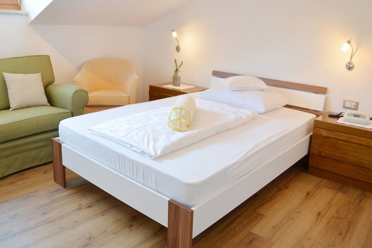 A modern bedroom with a single bed, a green sofa, and a chair.