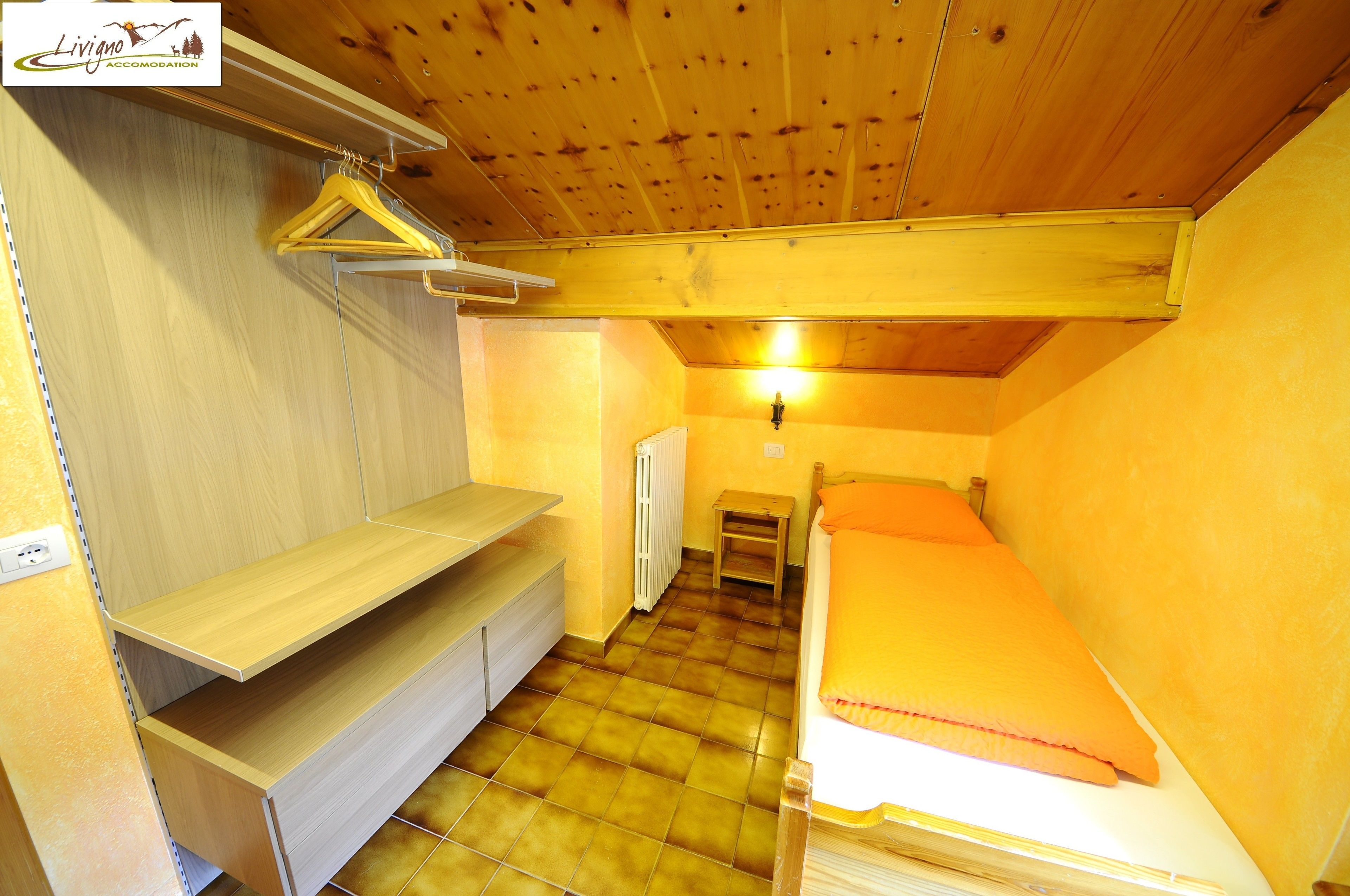 A compact room with a bed, a bench, and a small table.