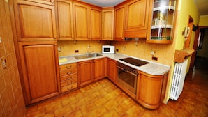 A kitchen with wooden cabinets, a microwave, a sink, and an oven. - Residence Casa Longa (Livigno)