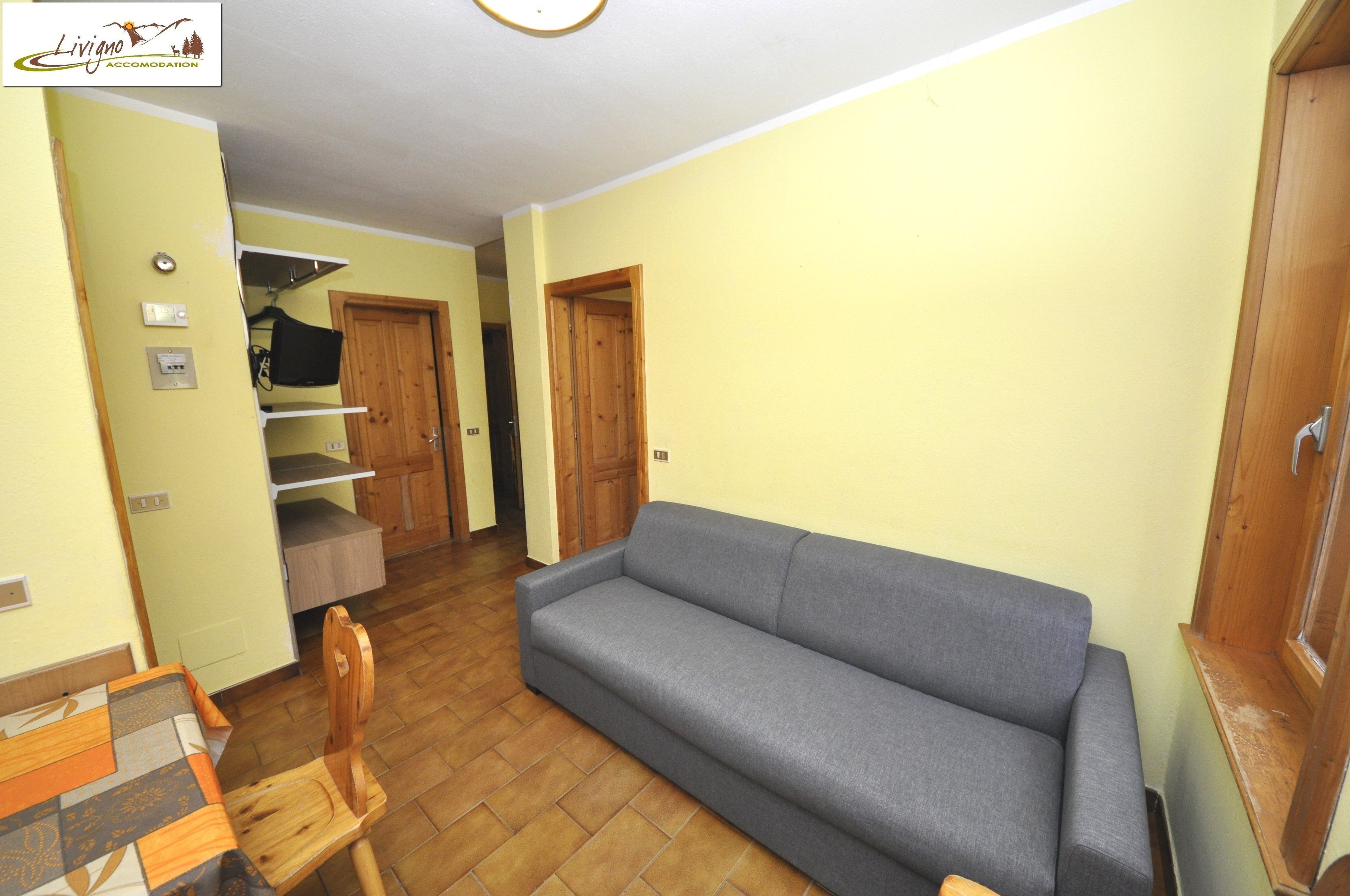 A living room with a sofa, a wooden chair, a small table, and a wooden cabinet.