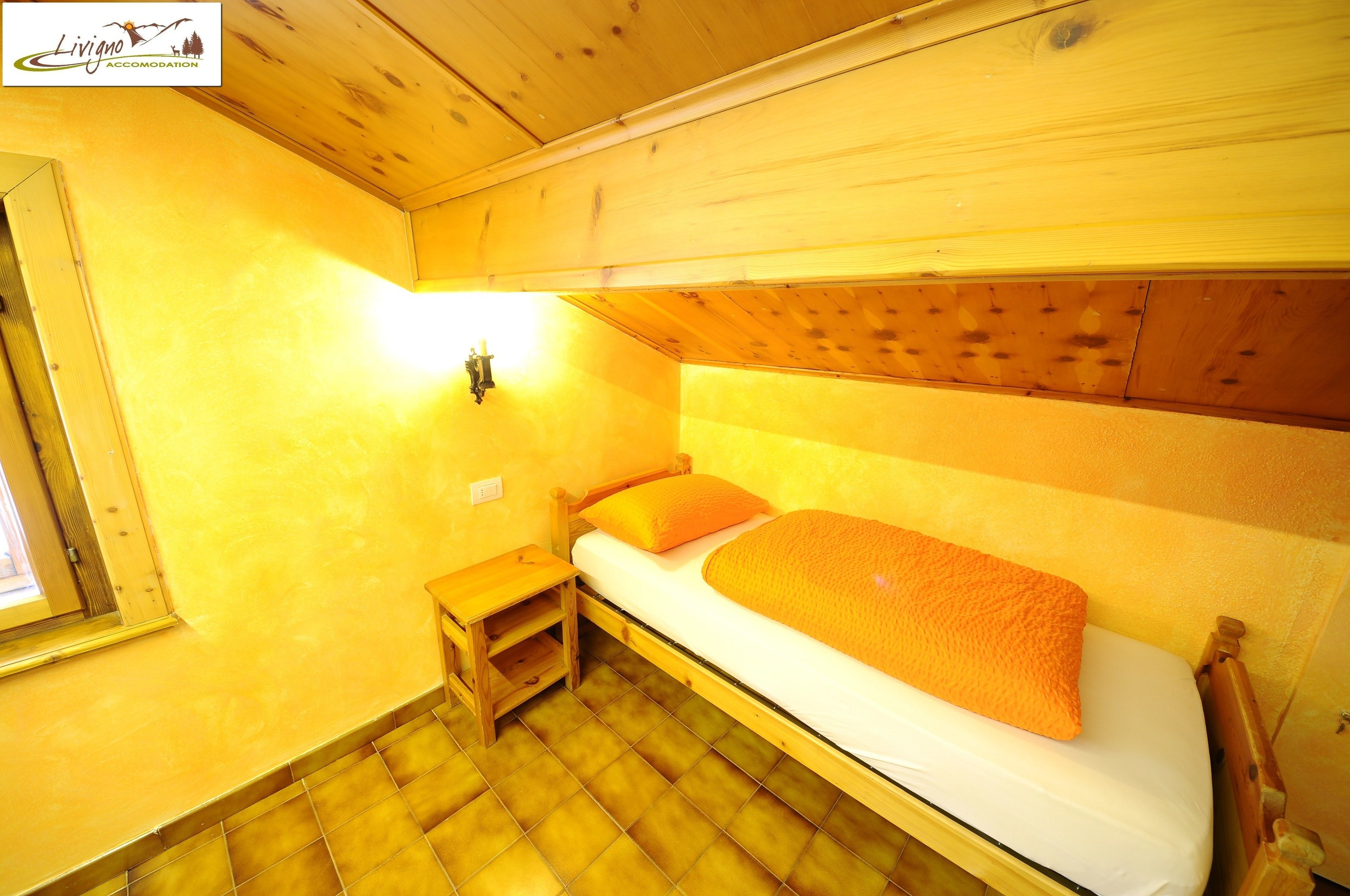 Ein kleines, gemütliches Zimmer mit einem Einzelbett, einem Nachttisch und einem Fenster.