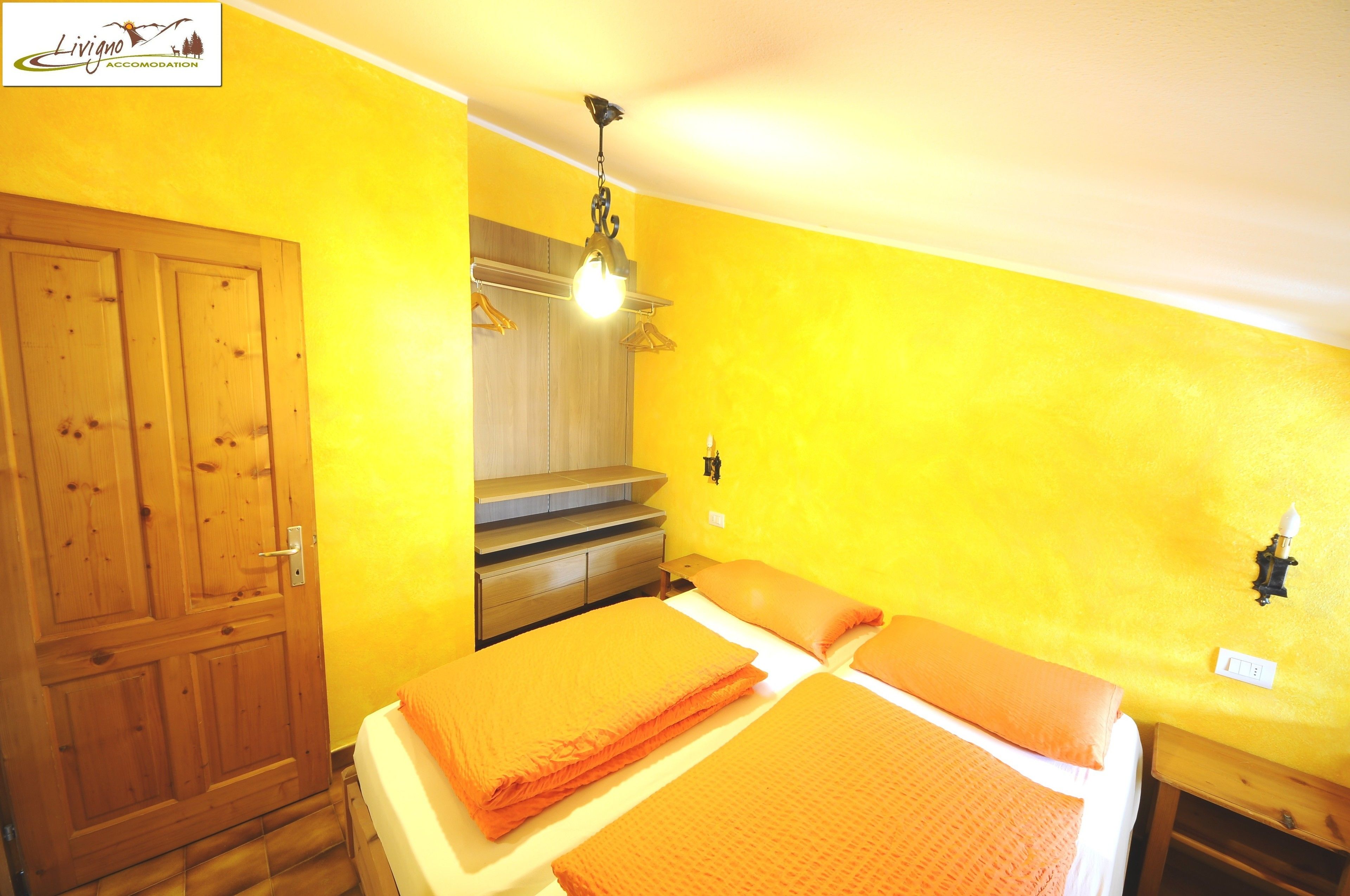 A room with a bed, wooden wardrobe, and a small desk.