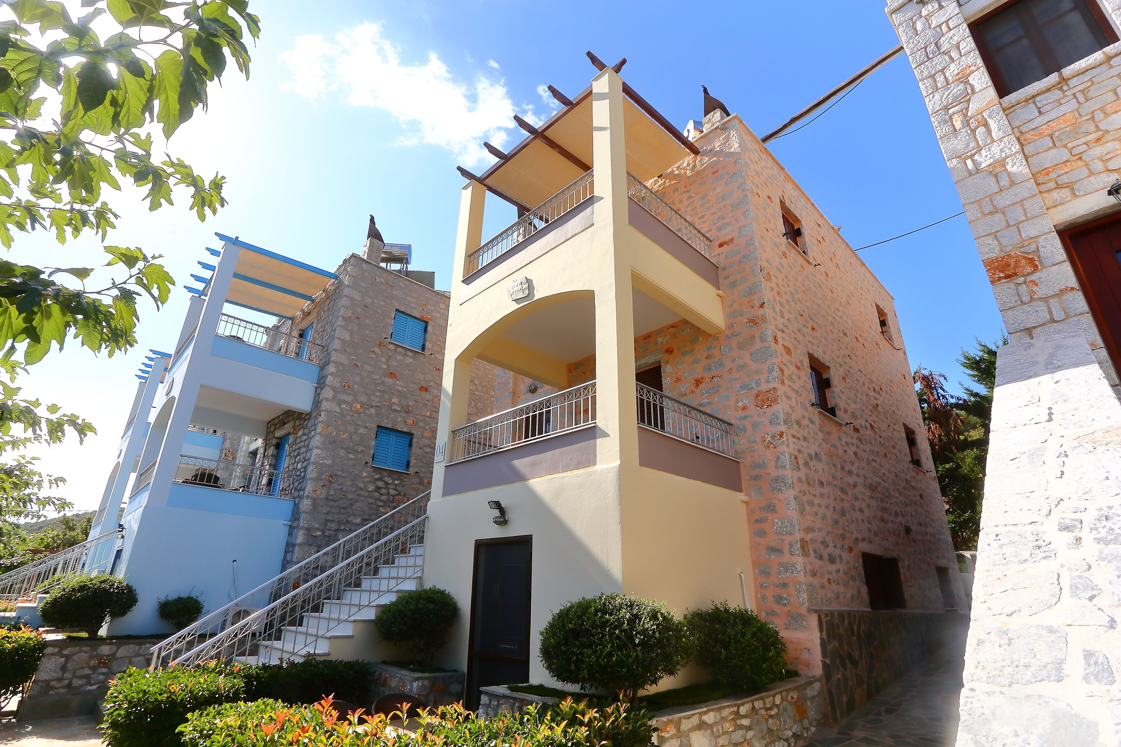 Un edificio de dos pisos con balcón, una escalera y una puerta.
