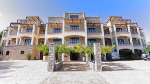 A multi-story hotel with a stone facade, balconies, and a clear sky. - Vathi Hotel (East Mani)