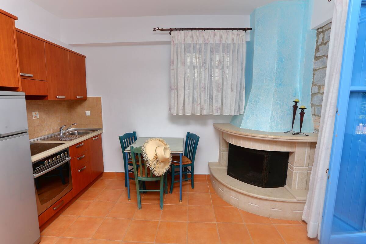 A compact kitchen with wooden cabinets, a built-in oven, and a dining table with chairs.
